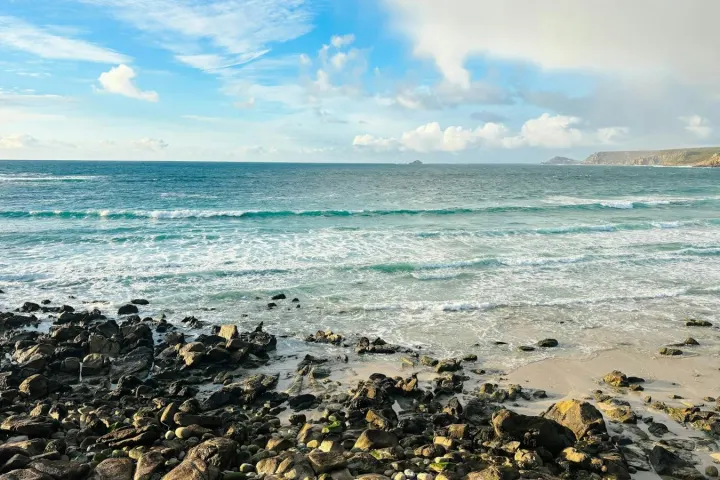Waves breaking on a pebbly beach under a blue sky