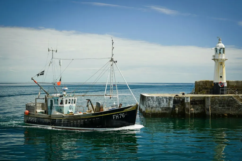 A fishing boat heading out past the harbour lighthouse