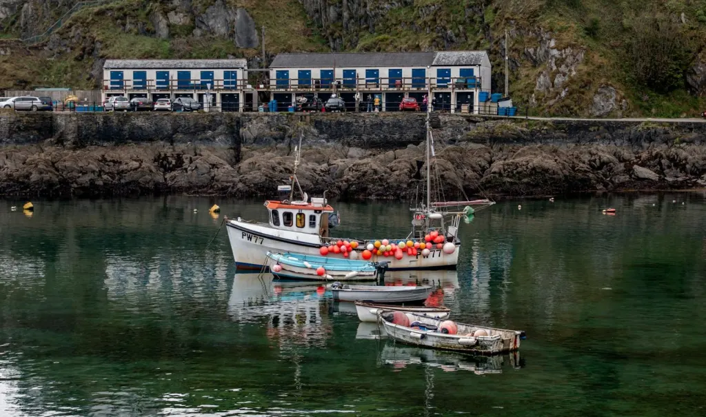 Small boats on still water below a row of quayside buildings