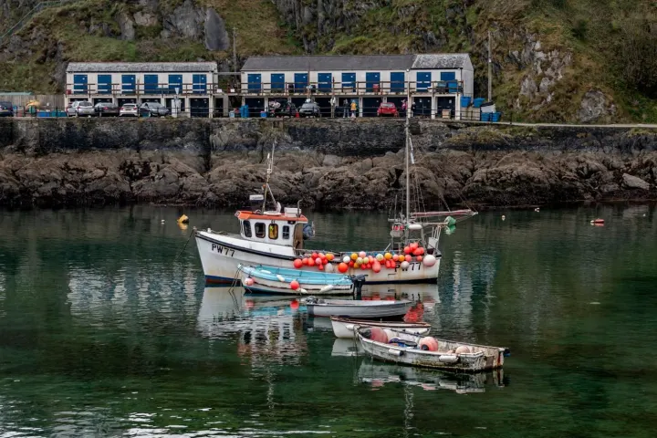 Small boats on still water below a row of quayside buildings