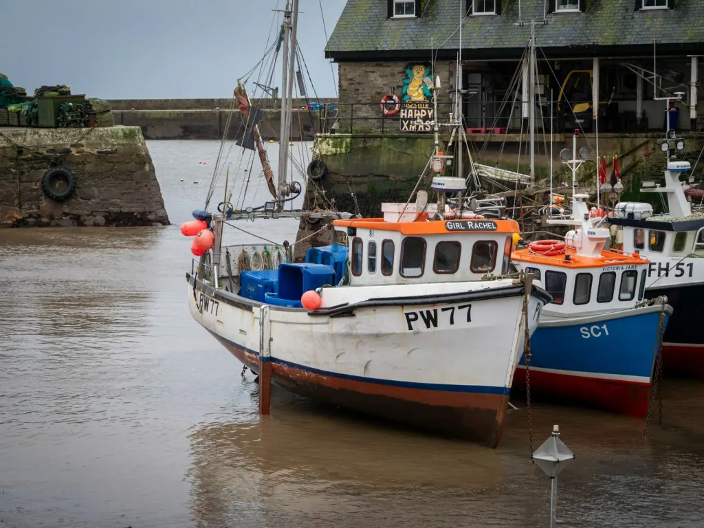 Fishing boats moored in a small stone harbour on a bright morning