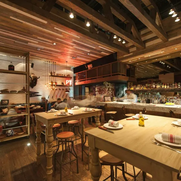 Wooden tables in front of an open kitchen and bar