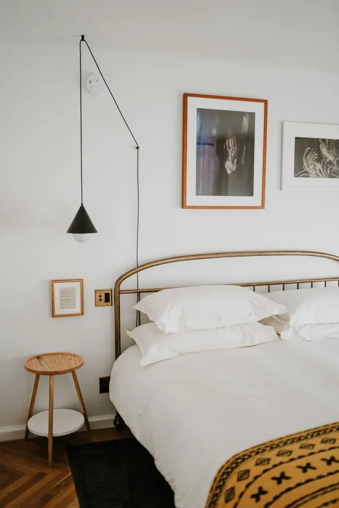 Bright bedroom with a brass bedstead, white linen and framed prints