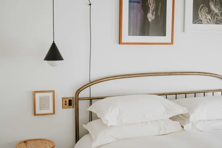 Bright bedroom with a brass bedstead, white linen and framed prints