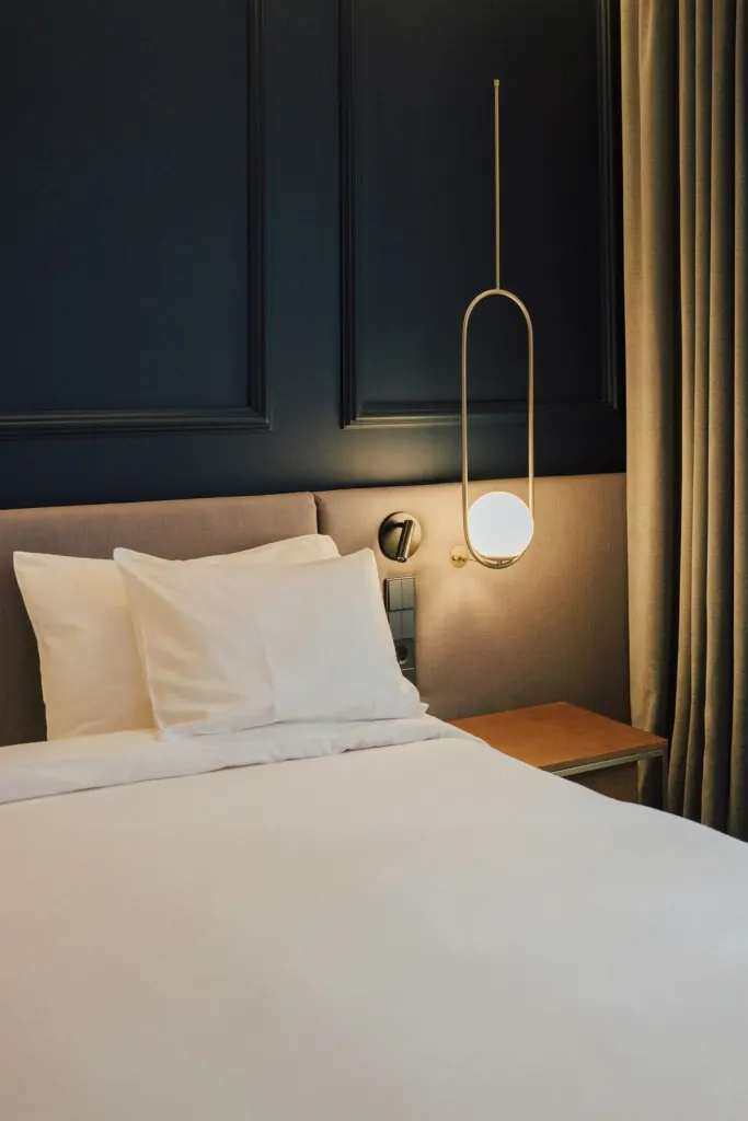 Cosy room with a white bed, a globe lamp and warm wooden panelling
