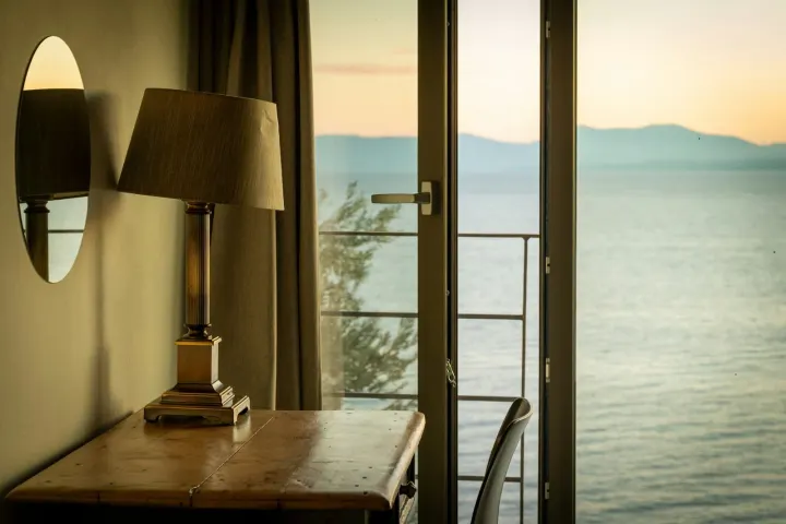 View from a bedroom balcony door over calm sea at sunset