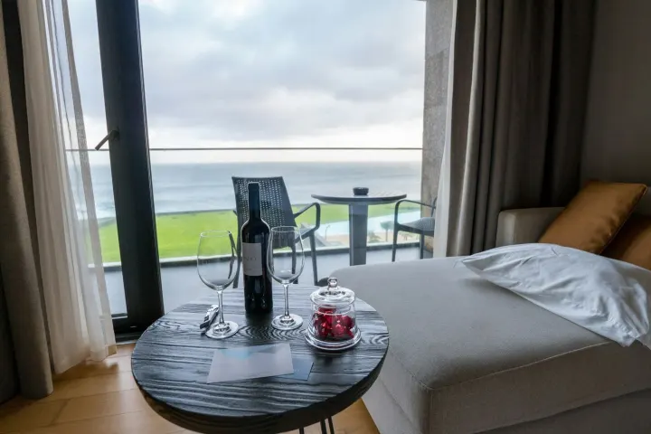 Balcony table with a bottle of wine and glasses looking out to sea